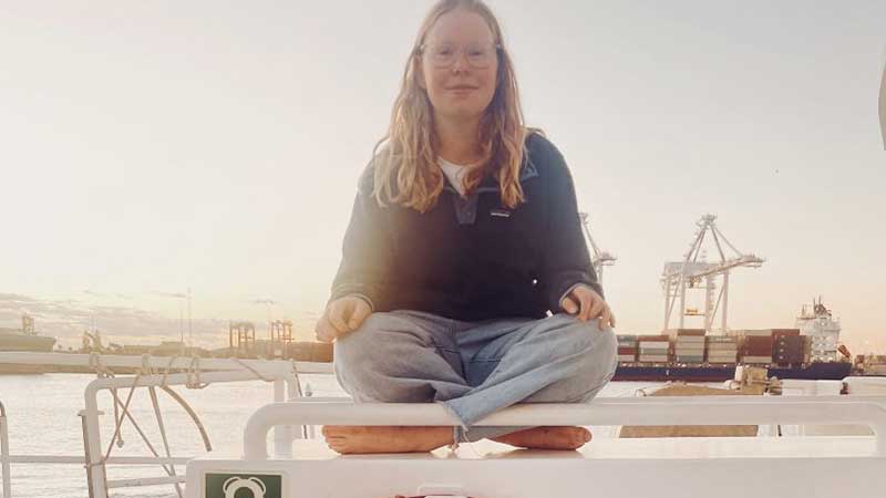 Emma from SS4C seated at the bow of the Rainbow Warrior at dusk in Fremantle